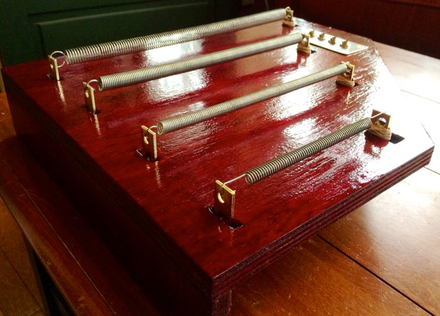 The Oxblood, an electro-acoustic instrument consisting of four compression springs amplified by contact microphones. Each spring consists of a different thickness and tension and is suspended across the instrument’s solid wooden body, attached to steel L-shaped brackets. A handmade contact microphone is attached to each set of brackets in order to directly amplify the vibrations of the performers interactions with each spring.